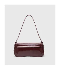 Burgundy patent leather baguette shoulder bag detail, minimalist design with curved bottom.