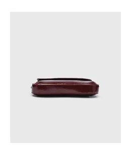 Red patent leather baguette bag bottom detail view, sleek compact flap shoulder handbag.