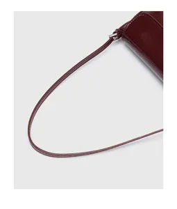 Wine red patent leather shoulder bag strap detail, elegant minimalist fashion accessory design.