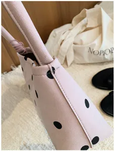 Close-up detail of stylish pink suede handbag with black polka dots, elegant aesthetic.