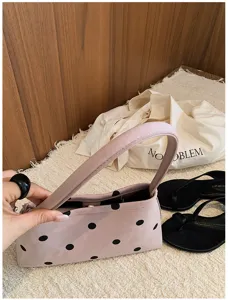 Detail shot of the pink polka dot underarm bag, featuring a minimalist casual style handle.