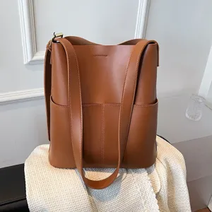 Minimalist brown bucket bag for women, stylish large capacity shoulder and crossbody design.