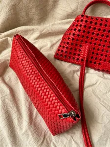 Close-up detail of red woven leather handbag set, showing exquisite intrecciato texture and zipper.