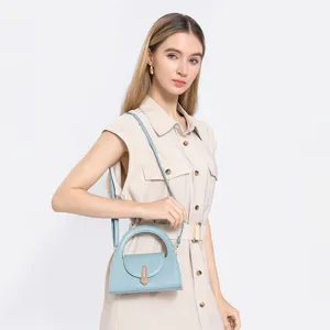 Detailed view of the light blue semi-circular crossbody bag with metal lock and handle.