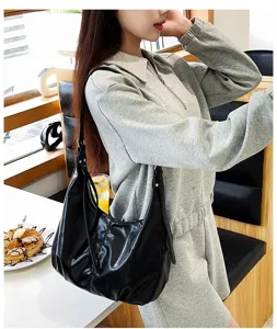 Escena de estilo de vida en cafetería con bolso de hombro holgado negro puesto.