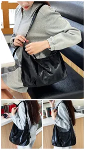 Vista detallada del bolso de hombro negro flexible llevado por la modelo con textura suave.