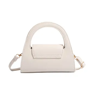 Detailed view of the elegant white trapezoid top-handle handbag with gold tone hardware.