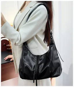 Bolso de hombro negro de cuero con diseño holgado, estilo elegante bajo el brazo y cremallera.