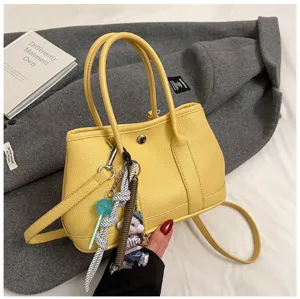 Detailed view of yellow PU leather tote shoulder bag with cute keychain charm accessory.