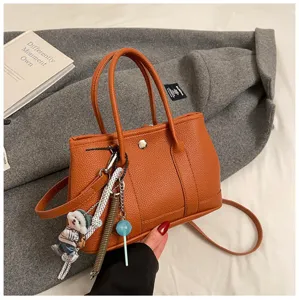 Orange leather tote bag with cute charms, stylish shoulder and crossbody design for women.