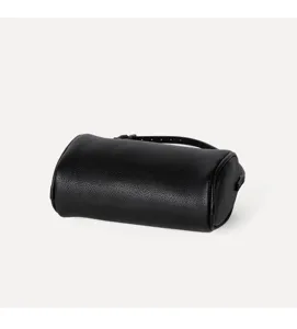Close-up view of the black pebbled leather texture and minimalist cylinder bag design details.