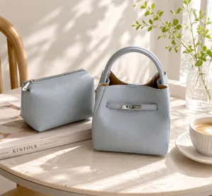Élégant sac à main en cuir bleu clair avec fermoir tournant et trousse assortie.