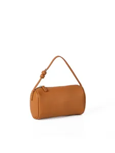 Close-up detail of brown pebble grain cylinder handbag, minimalist style leather purse.