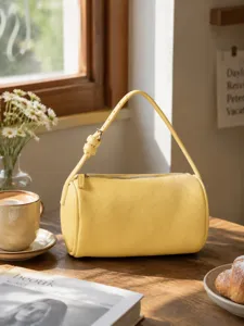 Yellow cylindrical shoulder bag detail showcasing pebble grain texture and adjustable strap.