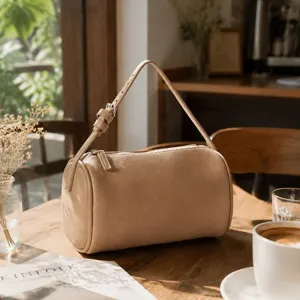 Minimalist beige cylinder shoulder bag, chic daily accessory with smooth zipper closure.