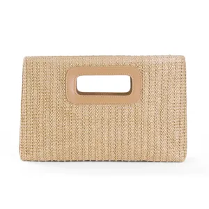 Close-up detail of a summer straw woven clutch bag with a stylish cutout leather handle.