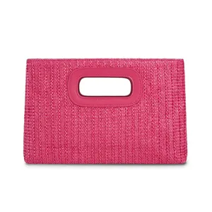 Close-up detail of the pink straw woven clutch bag with stylish leather-trimmed cutout handle.