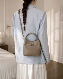 Vue détaillée d'un sac seau en cuir taupe porté avec un élégant blazer bleu clair.