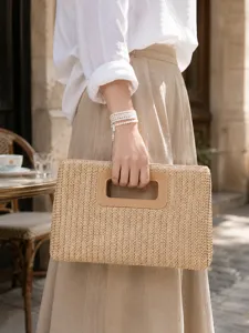 Detail view of a summer straw clutch bag featuring a chic leather cutout handle for vacation.