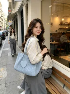 Detailed view of the stylish woven leather tote bag with heart charm, perfect for commuting.