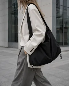 Detail view of minimalist black nylon hobo shoulder bag showing large capacity and design.