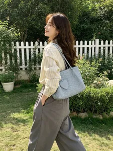Chic women's woven shoulder bag in light blue with a cute heart charm, ideal for daily commute.