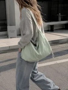 Detailed street view of a light green nylon hobo shoulder bag, casual everyday style.