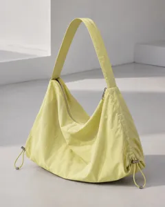 Detail shot of the minimalist yellow nylon hobo shoulder bag showing texture and hardware.