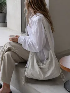 Detail shot showing large beige nylon hobo shoulder bag styled in minimalist daily commuter scene.
