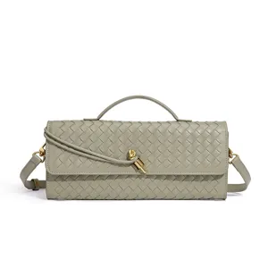 Detailed shot of trendy green woven leather shoulder baguette bag with chic metal knot handle.