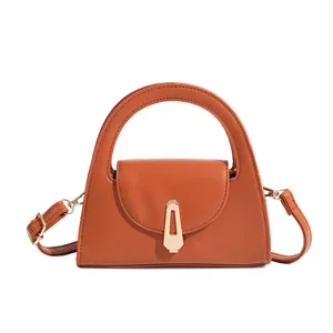 Detailed close-up view of the brown semi-circular women handbag with metal clasp and strap.