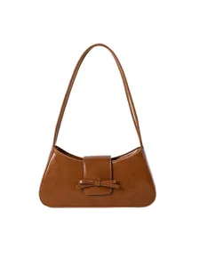 Brown patent leather baguette shoulder bag with cute bow detail, minimalist underarm style.