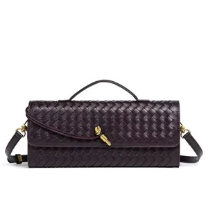 Detailed view of dark woven leather baguette bag with chic golden knot clasp and strap.