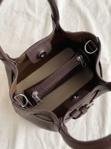 Detailed top view of dark brown leather bucket bag interior with zipper pocket and snap closure.