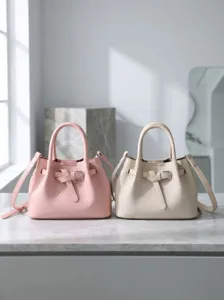 Detail shot of stylish leather bucket handbags in pink and beige with sleek buckle straps.