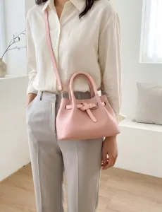 Pink bucket handbag with top handles and stylish belt detail, perfect for casual daily wear.