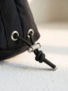 Black nylon shoulder bag drawstring detail, silver metal eyelets, and adjustable cord lock.