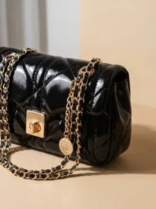 Sac à bandoulière noir en cuir verni matelassé avec chaîne dorée et fermoir tourniquet chic.