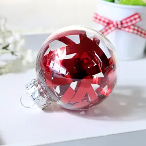 Nahaufnahme des transparenten Kunststoff-Christbaumkugel-Details mit roter Glanzfaser.