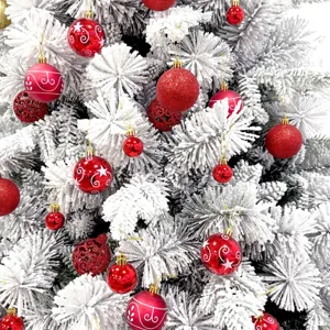Detailaufnahme festlicher roter Weihnachtskugeln hängend an einem wunderschönen schneeweißen Baum.