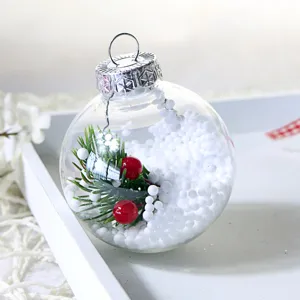 Transparente Christbaumkugel mit weißer Füllung, Tannennadeln und roten Beeren für Weihnachtsdeko
