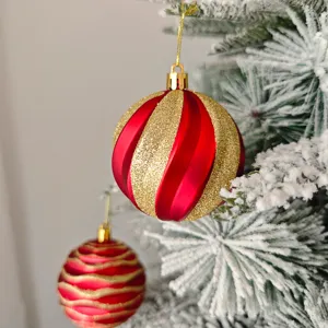 Nahaufnahme von roten und goldenen Glitzer-Weihnachtskugel-Ornamenten am Baum.