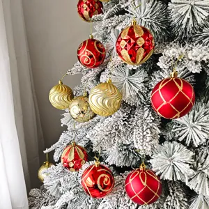 Detailaufnahme von roten und goldenen Weihnachtskugeln an verschneiten Tannenzweigen.
