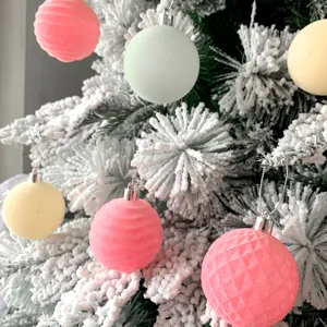 Nahaufnahme von beflockten Pastell Christbaumkugeln mit weicher schneebedeckter Textur Detail.