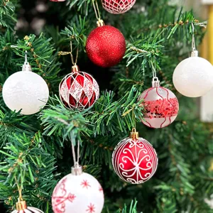 Nahaufnahme festlicher rot-weißer Christbaumkugeln mit Glitzer und bemalten Mustern.