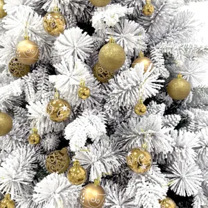 Beflockter künstlicher Weihnachtsbaum mit goldenen Christbaumkugeln und Anhängern geschmückt.