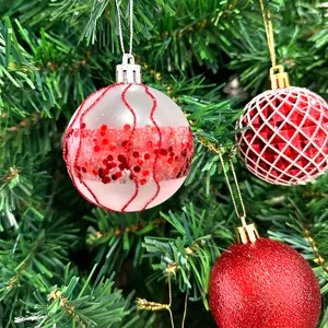 Nahaufnahme festlicher Christbaumkugeln mit rotem Glitzer und gemustertem Feiertagsdekor.