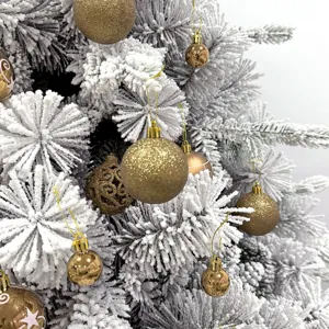 Nahaufnahme von luxuriösen goldenen Weihnachtskugeln an verschneiten Tannenbaumzweigen.