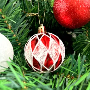 Nahaufnahme einer gemalten 6cm Plastik Weihnachtskugel hängend an einem Tannenbaum.