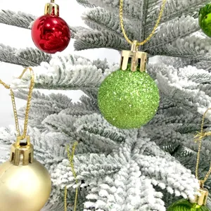 Nahaufnahme kleiner begrünter Christbaumkugeln, bunte glänzende und glitzernde Dekoration.